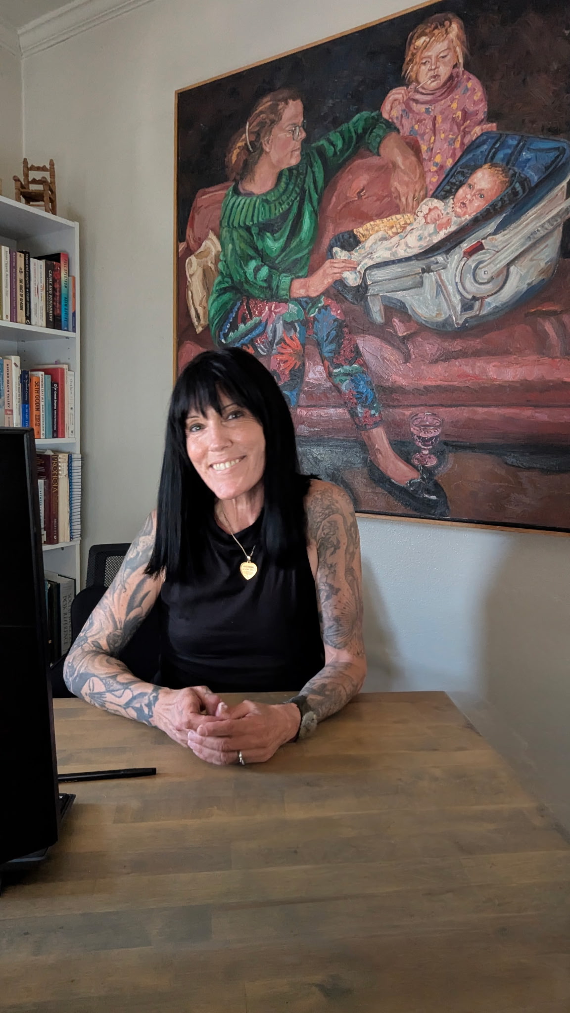 Bre Sheehan seated at her desk beneath a large family portrait painting